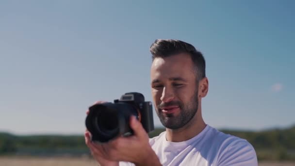 Un hombre sonriente toma una foto en la cámara — Vídeos de Stock