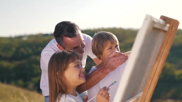 Papá sonriente y los niños dibujan un cuadro — Vídeo de stock