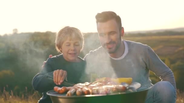 Pai e filho cozinhar salsichas na grelha — Vídeo de Stock