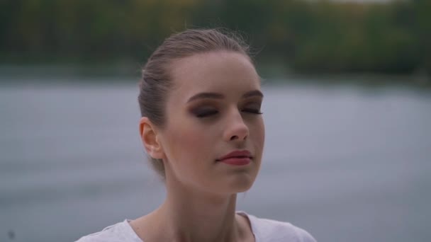 La chica está meditando cerca del lago — Vídeo de stock