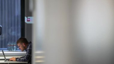 Adam üstünde laptop ofiste çalışıyor.