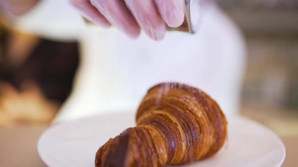 Il cuoco spruzza un croissant con zucchero a velo — Video Stock