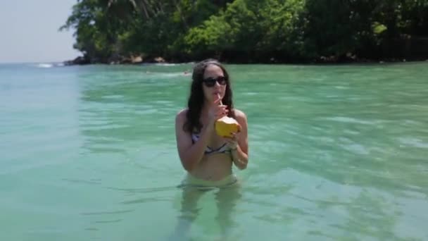 Девушка пьет коктейль в океане — стоковое видео