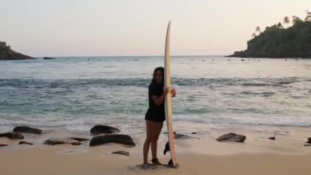Девушка веселится с доской для серфинга у океана — стоковое видео