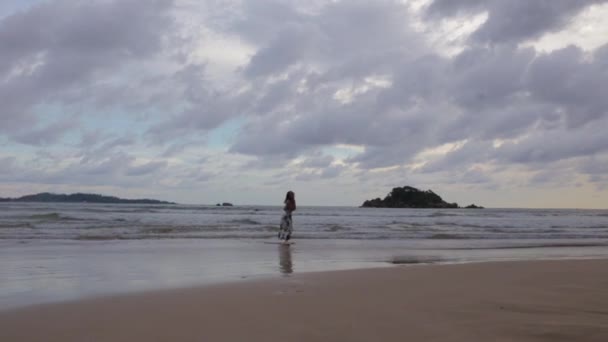 Meisje in een jurk die wandelen op de oever van de Oceaan — Stockvideo