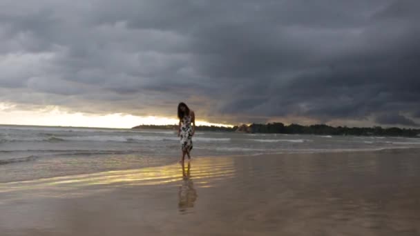 Fille dans une robe marchant sur le rivage de l'océan au coucher du soleil — Video