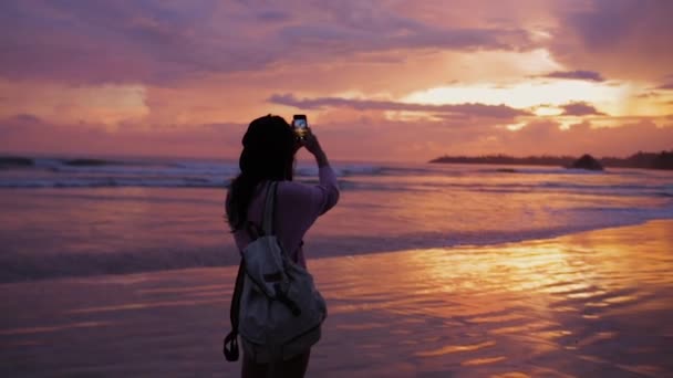 Lány vesz egy fényképet, gyönyörű naplemente az óceán — Stock videók