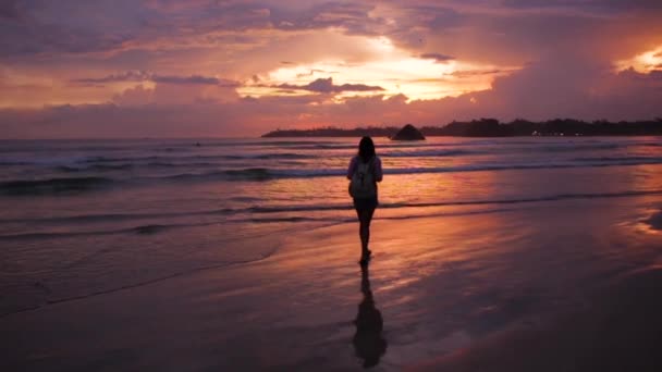 Menina andando ao pôr do sol junto ao oceano — Vídeo de Stock