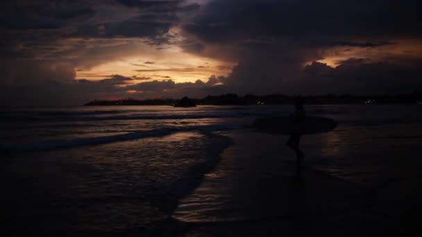 Meisje met surfboard bij zonsondergang — Stockvideo