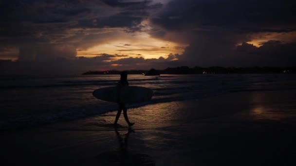 Hombre con tabla de surf en el hermoso atardecer junto al océano — Vídeo de stock