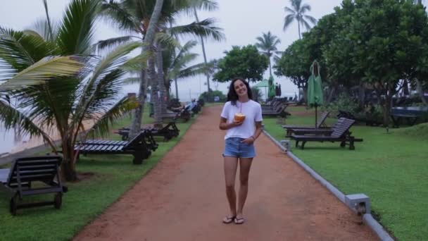 Девушка гуляет по набережной с пальмами — стоковое видео