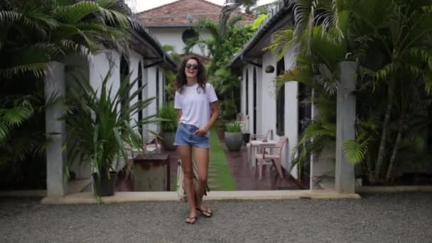 Mädchen mit Rucksack in der Nähe einer Villa mit Palmen — Stockvideo
