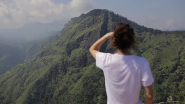 Menina olha para o vale da floresta de um topo — Vídeo de Stock