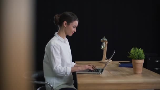 Дівчина друкує на ноутбуці в офісі — стокове відео