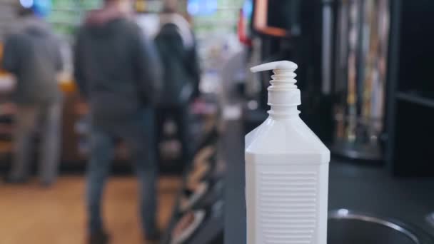 Un hombre usa un dispensador con un desinfectante en un lugar público — Vídeos de Stock