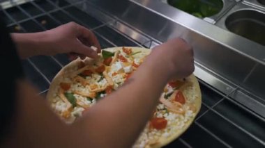 Aşçı pizzaya malzeme koyar.