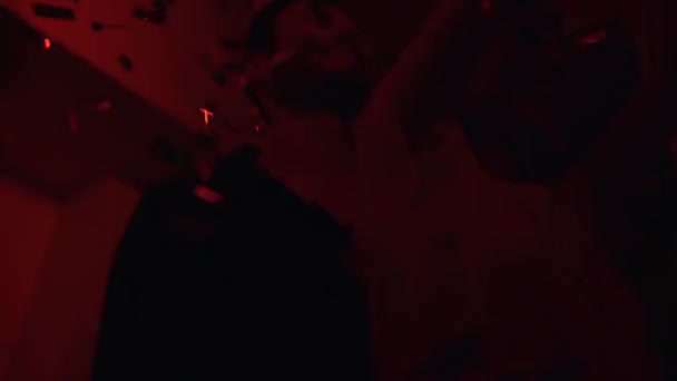 Çift kırmızı ışıklar ve konfetilerin olduğu bir partide eğleniyor. — Stok video