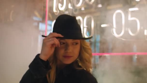 Dívka v kouřové ulici stojí na neonové ceduli — Stock video
