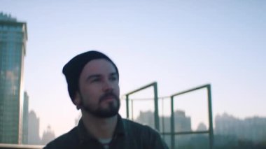 Moda adamı şehrin arka planında çatıda yürüyor.