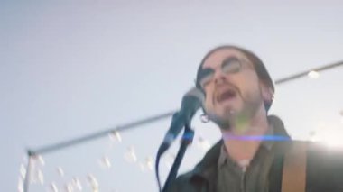 Müzisyen enerjik bir şekilde açık havada konser veriyor.