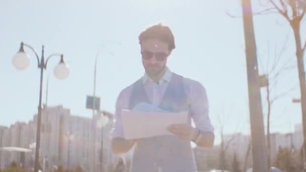 Homme d'affaires regarde à travers les documents se promenant dans la ville — Video