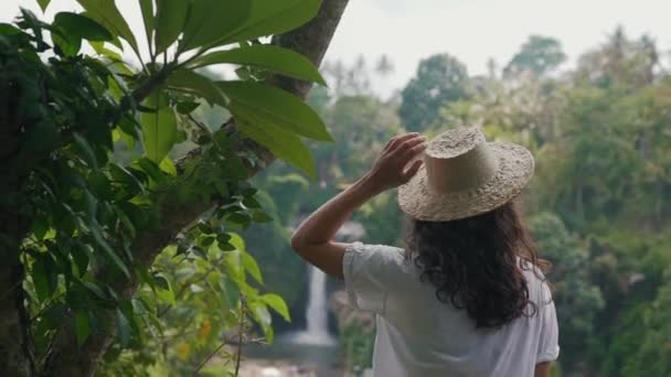 Meisje met hoed bij een waterval in Bali — Stockvideo