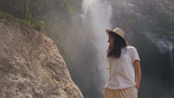 Tourist girl smiling on the background of a waterfall — Stock Video