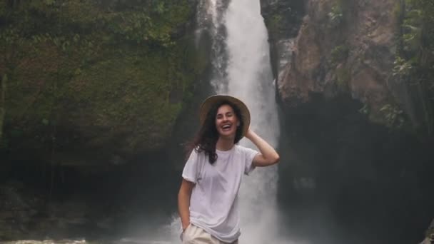 在瀑布背景上戴草帽的女孩 — 图库视频影像