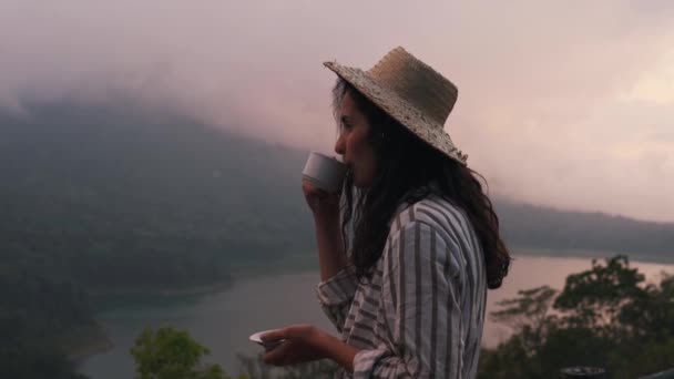 Turist flicka i en halm hatt drycker kaffe — Stockvideo