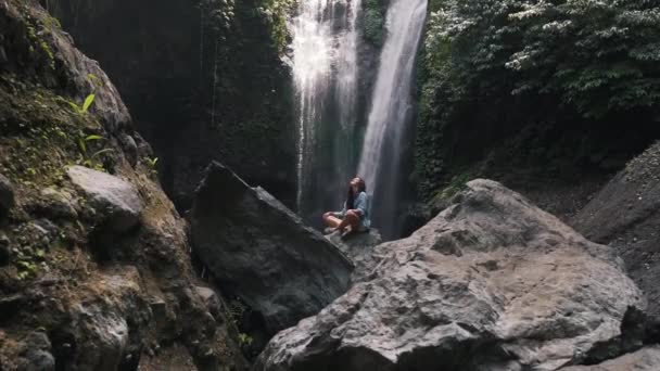 Menina descansando no fundo de uma cachoeira — Vídeo de Stock