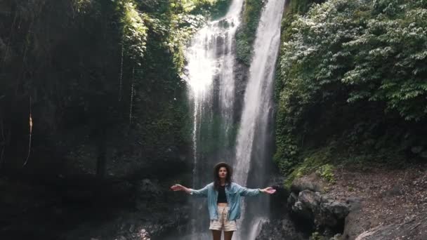 Turist flicka på bakgrunden av ett vattenfall i Bali — Stockvideo