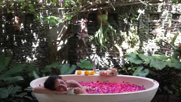 Fille est relaxant dans la salle de bain avec des fleurs en plein air — Video