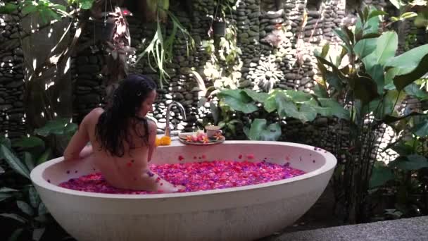 Дівчина розслабляється у ванній кімнаті з квітами в природі — стокове відео