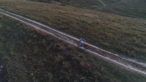 Vista aérea del tipo está en bicicleta fuera de la ciudad — Vídeos de Stock
