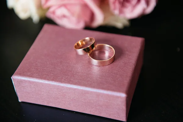 Snubní prsteny s růžovými růžemi na dřevěné pozadí — Stock fotografie