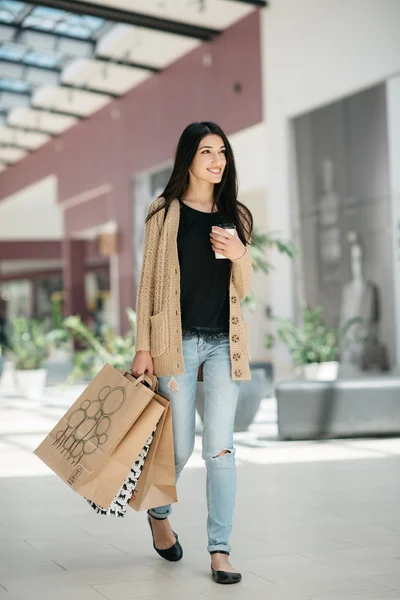 Menina bonito atraente em com os sacos de compras e bebida quente em sua mão — Fotografia de Stock