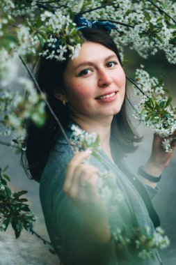 Genç güzel kız baharda çiçek açan kiraz ağacının yanında