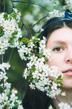 Genç güzel kız baharda çiçek açan kiraz ağacının yanında