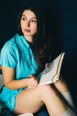 Genç bir kadın evde kalemle resim çiziyor.