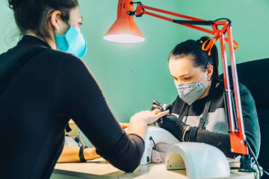 Bir manikürcü müşterisiyle çalışır ve bahar manikürü yapar..