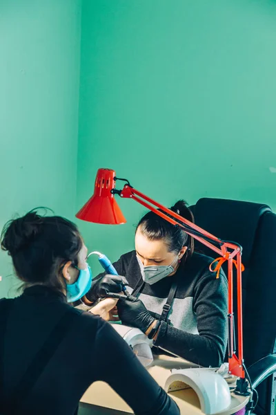 Bir manikürcü müşterisiyle çalışır ve bahar manikürü yapar..