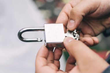 Adam elinde anahtarla bir kilit tutuyor..