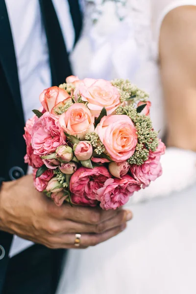 Gelin ve damat pembe bir buket tutuyorlar.