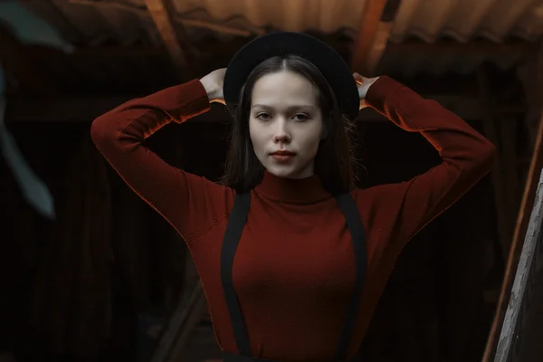 Yakın çekim portre bir güzel genç moda kadınların. Lady koyu gri arka plan üzerinde poz. Model giyen şık şapka çapında ekledi. Kız kameraya benziyor. Kadın moda. Tonda