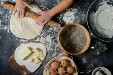 Boy with chef hat preparing dough - kneading and stretching. Top view.