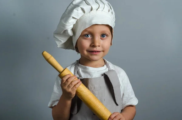 Smiling little cook with rolling pin, isolated on gray background — ストック写真