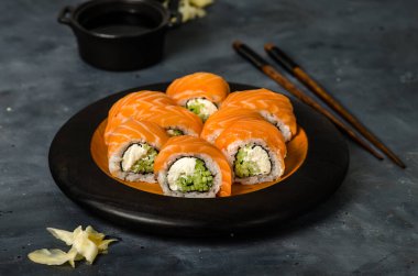 Somonlu Philadelphia suşisi, füme yılan balığı, salatalık, avokado, krem peynir, kırmızı havyar. Suşi menüsü. Japon yemeği..