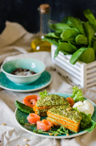 Healthy breakfast or lunch. Carrot-spinach cake with red fish, poached egg, pine nuts, lettuce and micro green.