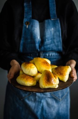 Geleneksel ev yapımı fırında köfte ya da patates ve lahana ile turta. Köy usulü hamur mayasından yapılmış fırında Rus turtası. Mavi önlüklü bir kadın elinde turta tutuyor..