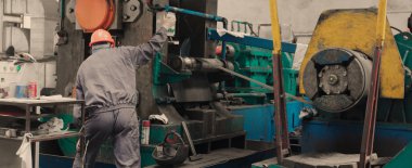 Metal endüstrisinde kontrol paneli üzerinde çalışan işçi işletim makinesi.